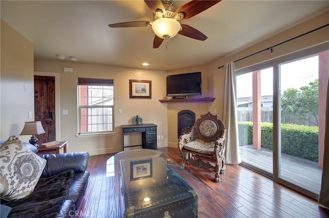 living area featuring a ceiling fan, wood finished floors, a fireplace, and baseboards