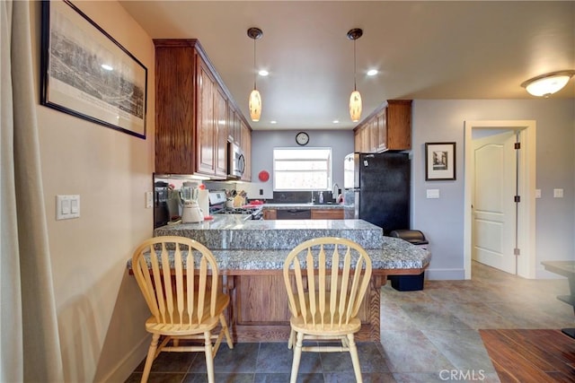 kitchen with a sink, stainless steel appliances, a peninsula, a breakfast bar area, and tile counters