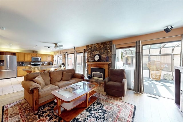 living room featuring a ceiling fan, visible vents, a healthy amount of sunlight, and light wood-style floors