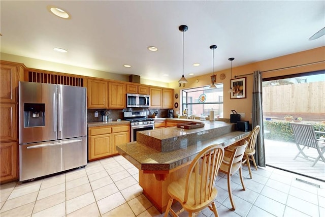 kitchen featuring stainless steel appliances, a breakfast bar area, tile counters, and light tile patterned flooring