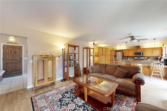 living area featuring baseboards, light wood-style floors, and ceiling fan