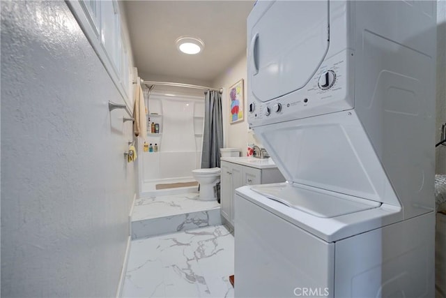 laundry room featuring stacked washer and dryer, marble finish floor, laundry area, and a textured wall