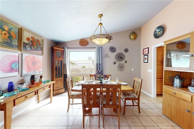 dining area featuring vaulted ceiling, light tile patterned floors, and baseboards