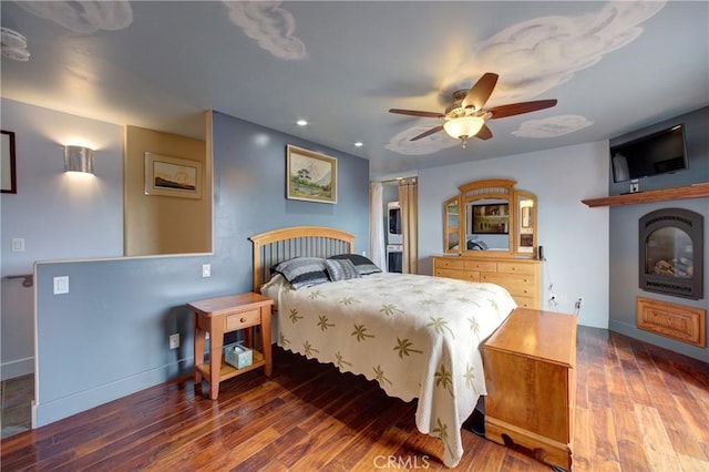 bedroom with wood finished floors, baseboards, recessed lighting, ceiling fan, and a glass covered fireplace