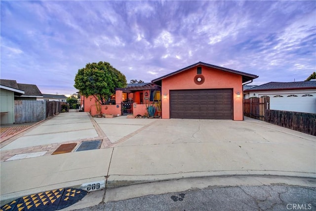 view of front of property with an attached garage, fence, driveway, and stucco siding