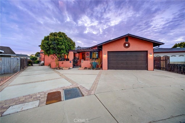 view of front of home featuring stucco siding, an attached garage, driveway, and fence