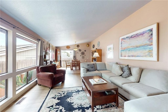 living room featuring visible vents, a textured ceiling, light wood-style floors, and lofted ceiling