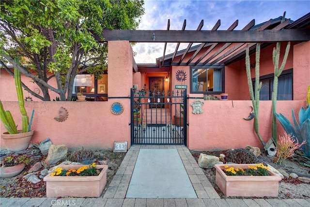 property entrance with a gate, fence, and stucco siding