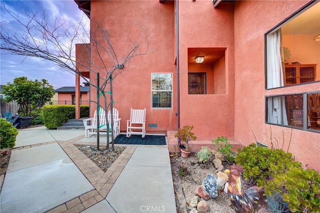 property entrance featuring stucco siding, a patio, and fence