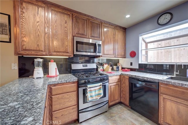 kitchen featuring decorative backsplash, brown cabinets, appliances with stainless steel finishes, and a sink