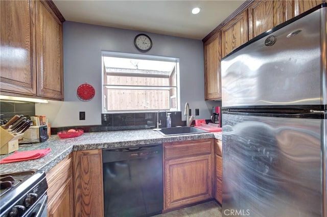 kitchen featuring a sink, freestanding refrigerator, range with gas cooktop, brown cabinetry, and dishwasher