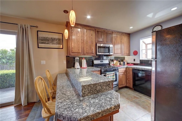 kitchen featuring pendant lighting, recessed lighting, brown cabinets, a peninsula, and stainless steel appliances