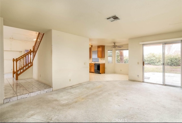 unfurnished living room featuring visible vents, light carpet, beverage cooler, a ceiling fan, and stairs