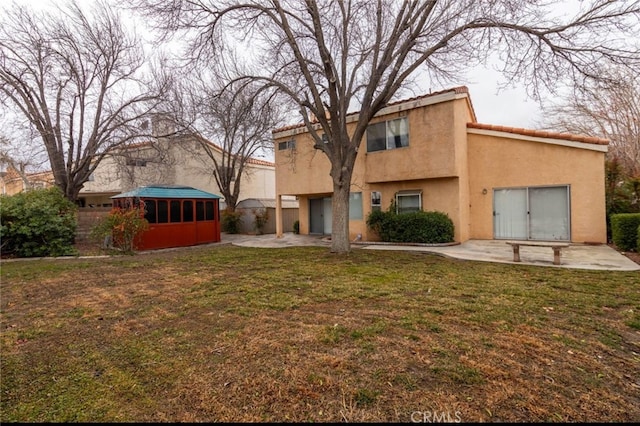 rear view of house with a yard, a patio area, fence, and stucco siding