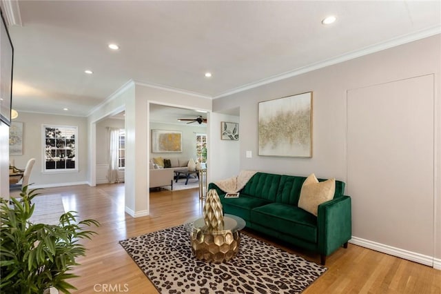 living area with recessed lighting, light wood-style floors, crown molding, baseboards, and ceiling fan