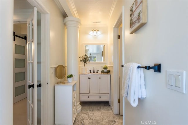 hallway with crown molding, decorative columns, visible vents, and a sink