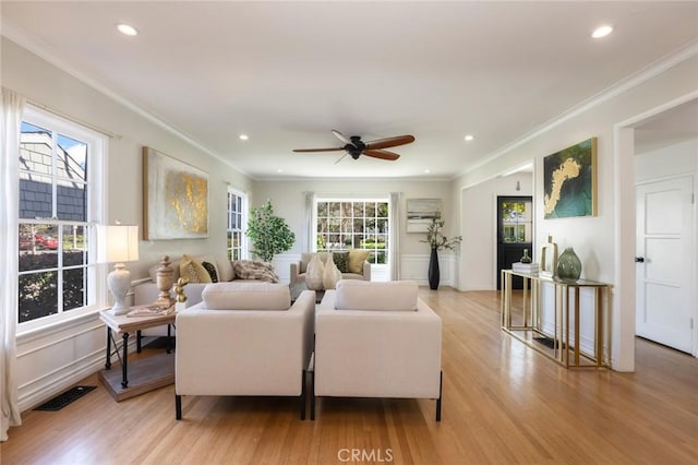 living area with light wood finished floors, visible vents, recessed lighting, and crown molding