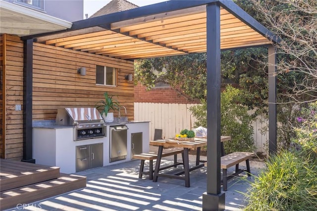 view of patio featuring outdoor dining space, an outdoor kitchen, grilling area, and fence