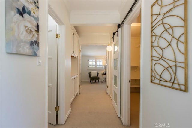 hall with a barn door, ornamental molding, and light carpet