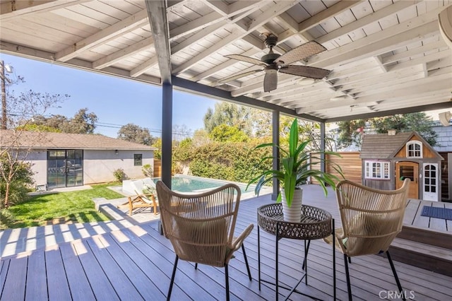 wooden terrace with an outdoor pool, an outdoor structure, and ceiling fan