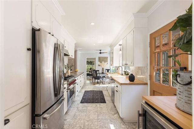 kitchen with butcher block countertops, backsplash, appliances with stainless steel finishes, and crown molding