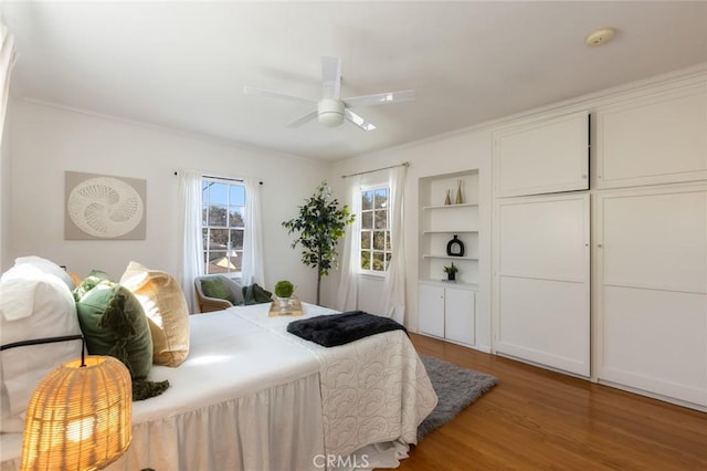 bedroom featuring ornamental molding, a ceiling fan, and wood finished floors