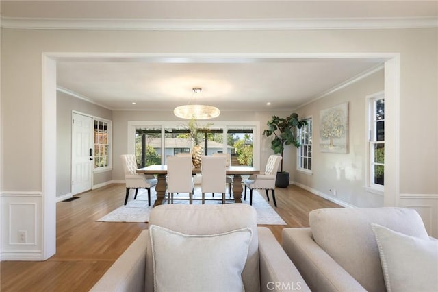 living area with wainscoting, light wood-type flooring, and ornamental molding