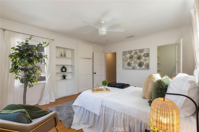 bedroom featuring visible vents, wood finished floors, a ceiling fan, and ornamental molding