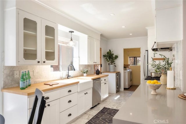 kitchen featuring washer and dryer, a sink, appliances with stainless steel finishes, white cabinets, and glass insert cabinets