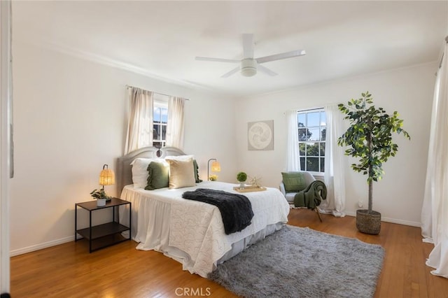 bedroom with multiple windows, wood finished floors, and baseboards