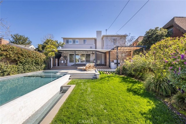 rear view of property with a lawn and an outdoor pool