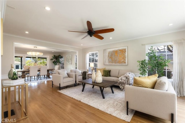 living area with plenty of natural light, crown molding, and light wood-type flooring