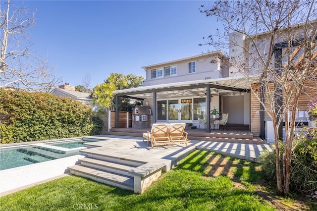 back of house with an outdoor pool, an in ground hot tub, and a wooden deck