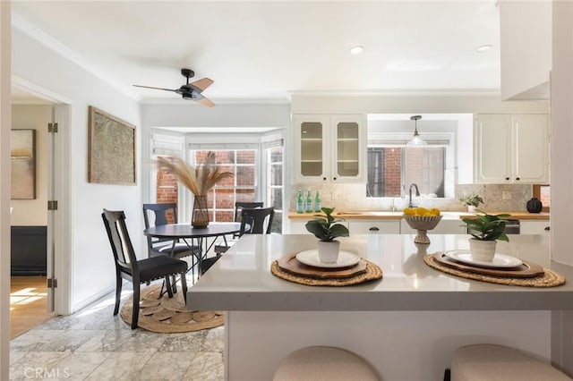 kitchen featuring white cabinetry, decorative backsplash, crown molding, and a kitchen bar