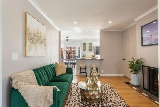 living room featuring recessed lighting, baseboards, light wood-style floors, and crown molding