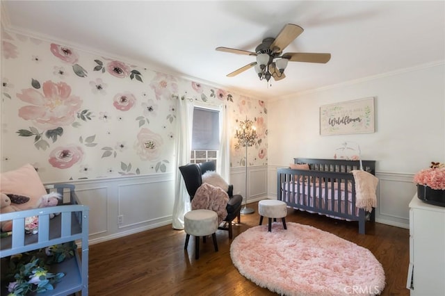 bedroom with a nursery area, wood finished floors, and wainscoting