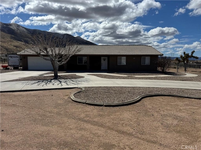 ranch-style house with a tiled roof, an attached garage, a mountain view, and driveway