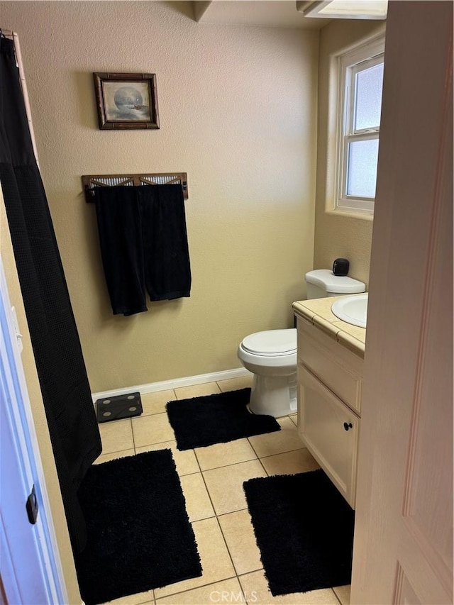 bathroom featuring baseboards, toilet, vanity, and tile patterned flooring