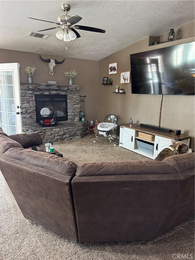 living room featuring visible vents, a stone fireplace, vaulted ceiling, a textured ceiling, and carpet flooring