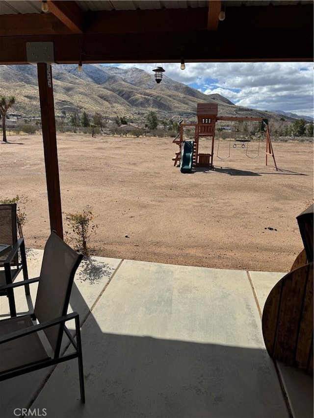 view of patio with a playground and a mountain view