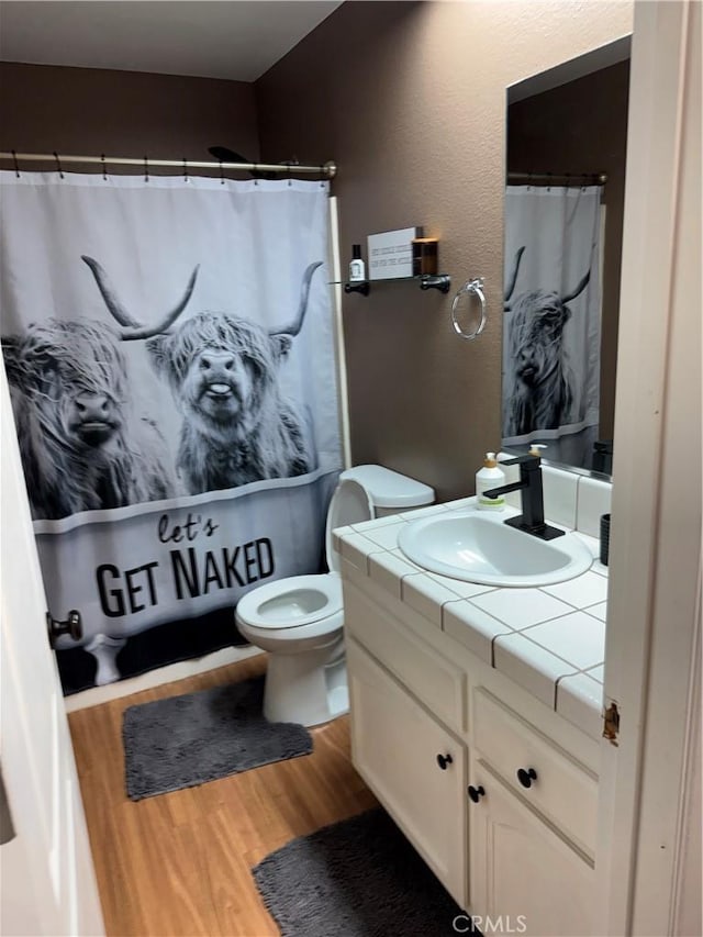 full bath with toilet, vanity, a shower with curtain, and wood finished floors