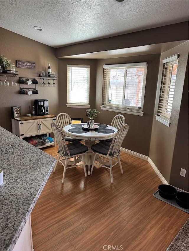 dining space featuring baseboards, light wood-style floors, and a textured ceiling