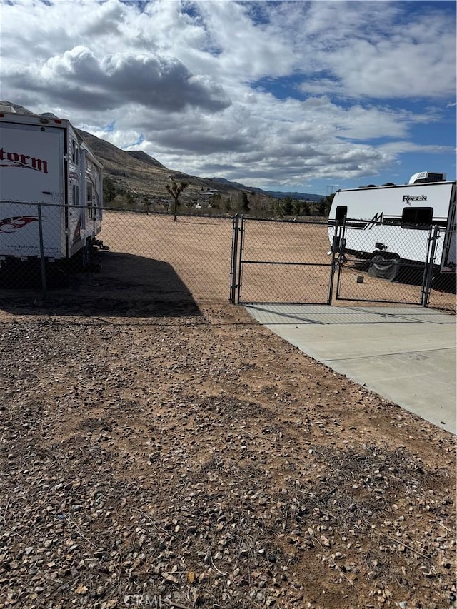 view of yard featuring a mountain view, fence, and a gate