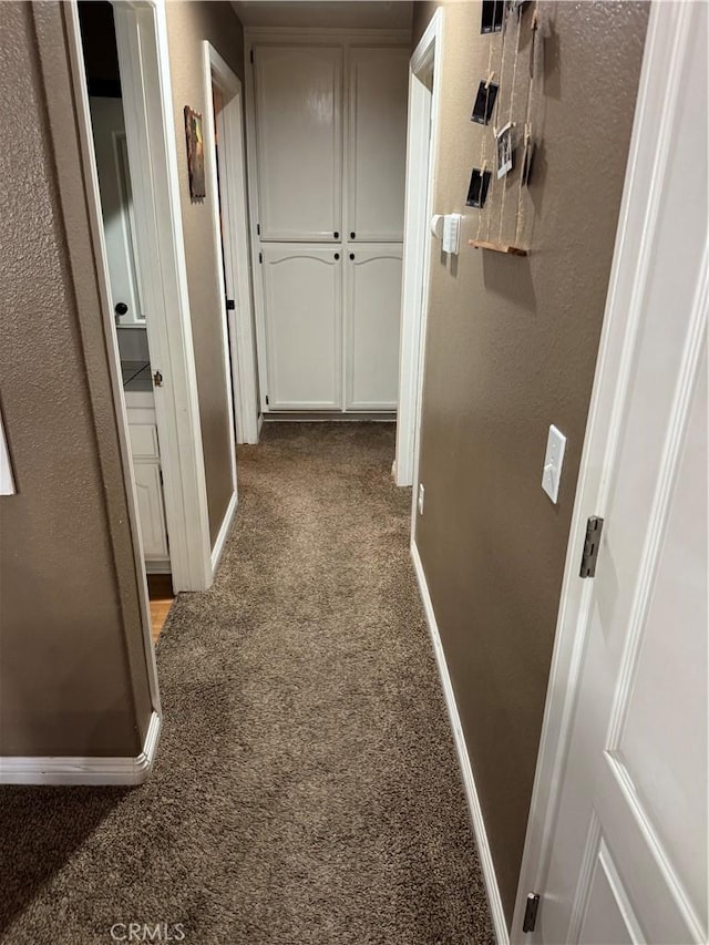 hall with baseboards, carpet flooring, and a textured wall