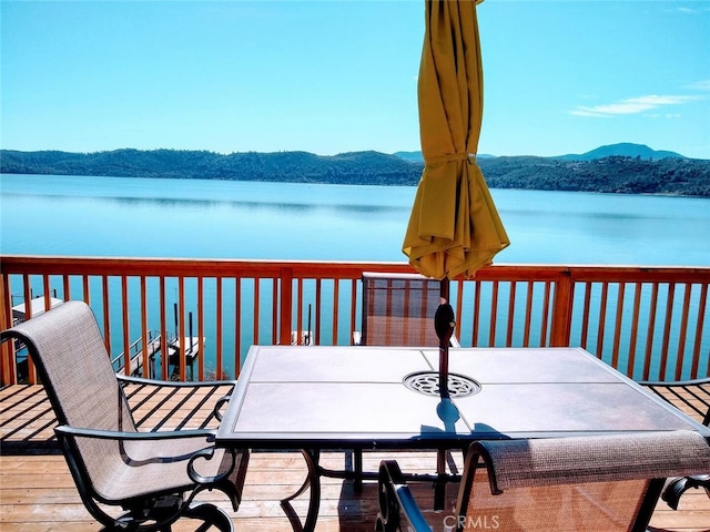 deck featuring outdoor dining area and a water and mountain view