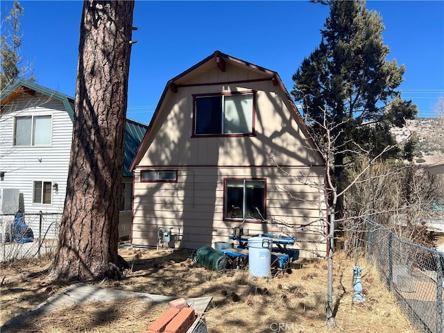 back of house with fence and a gambrel roof