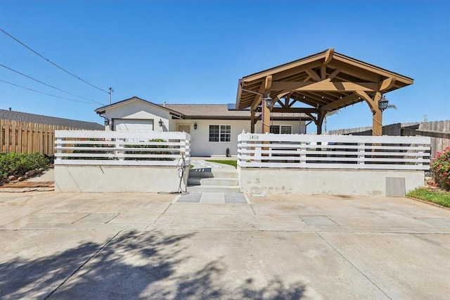 view of front facade featuring a gazebo, a fenced front yard, and stucco siding