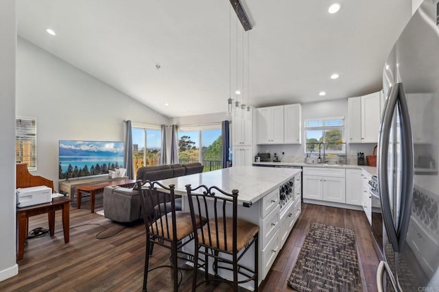 kitchen featuring freestanding refrigerator, dark wood-type flooring, white cabinets, a kitchen breakfast bar, and open floor plan