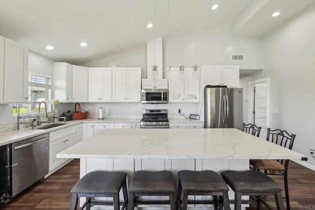 kitchen with visible vents, a center island, a breakfast bar, stainless steel appliances, and a sink