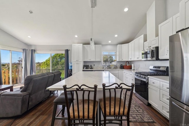 kitchen featuring a kitchen breakfast bar, dark wood-style floors, open floor plan, stainless steel appliances, and vaulted ceiling